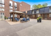 Thumbnail 27 of 28 - a courtyard with furniture and a gazebo in front of a brick building at Park 44 Apartments in St. Louis, MO, 63108