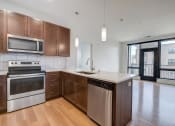 Thumbnail 11 of 36 - an empty kitchen with wooden cabinets and stainless steel appliances at Statesman Apartments, Franklin, WI