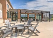 Thumbnail 3 of 36 - a patio with tables and chairs outside of a building at Statesman Apartments, Franklin, WI