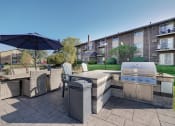 Thumbnail 12 of 37 - a backyard with an outdoor grill and table with chairs and an umbrella at The Greenway at Carol Stream, Illinois