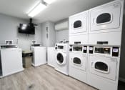 Thumbnail 25 of 28 - Laundry Center with Machines Next to Folding Counter at Park 44, St. Louis, Missouri at Park 44 Apartments, Missouri, 63108