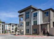 Thumbnail 4 of 40 - a row of apartment buildings on the side of a street at Hunters Creek Apartments, Denton, TX 76210