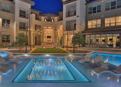Thumbnail 6 of 40 - a swimming pool with chairs in front of an apartment building at Hunters Creek Apartments, Texas