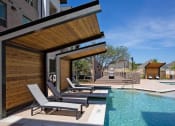 Thumbnail 10 of 40 - a pool with two lounge chairs next to a building at Hunters Creek Apartments, Texas, 76210
