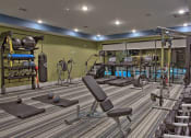 Thumbnail 16 of 40 - a gym with a lot of chairs and weights at Hunters Creek Apartments, Denton