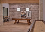 Thumbnail 23 of 40 - a pool table in a room with a brick wall at Hunters Creek Apartments, Texas, 76210