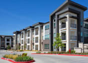 Thumbnail 24 of 40 - an apartment building with a red curb in front of it at Hunters Creek Apartments, Denton Texas