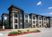 Thumbnail 25 of 40 - a row of apartment buildings with a parking lot at Hunters Creek Apartments, Denton, TX 76210