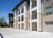 Thumbnail 26 of 40 - a row of brick apartment buildings with garage doors at Hunters Creek Apartments, Denton, TX