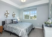 Thumbnail 48 of 69 - A bedroom with a bed, nightstand, and a window with a view of trees.
