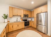 Thumbnail 3 of 9 - A kitchen with wooden cabinets and a stainless steel refrigerator.