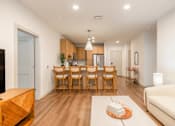 Thumbnail 5 of 9 - A modern living room with a dining area and a kitchen in the background.