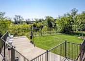Thumbnail 9 of 56 - A backyard with a deck and a metal fence.