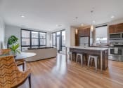 Thumbnail 5 of 36 - an open kitchen and living room with a large island with bar stools at Statesman Apartments, Franklin, Wisconsin