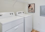 Thumbnail 9 of 36 - a washer and dryer in a laundry room with a painting on the wall at Statesman Apartments, Wisconsin 53132