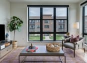 Thumbnail 29 of 36 - a living room with a large window and a couch and a table at Statesman Apartments, Wisconsin
