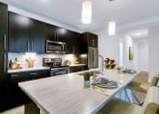 Thumbnail 18 of 52 - a kitchen with black cabinets and a wooden table at Aster Apartments, Beachwood