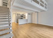 Thumbnail 12 of 28 - the living room and kitchen of a house with wood floors and a staircase at Park 44, St. Louis, MO, 63108
