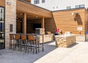 Thumbnail 11 of 22 - Outdoor kitchen and bar seating area at Timber Club Apartments, St. Peters, Missouri