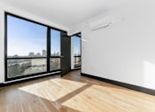 Thumbnail 13 of 29 - A room with a wooden floor and a large window overlooking a cityscape.