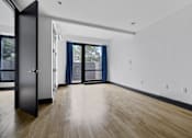 Thumbnail 20 of 29 - A room with a black door and wooden flooring.