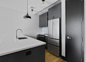 Thumbnail 21 of 29 - A modern kitchen with a white countertop and black cabinets.