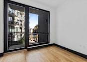 Thumbnail 17 of 29 - A room with a sliding glass door leading to a balcony with a railing.