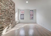 Thumbnail 4 of 7 - an empty living room with a brick wall and wood floors