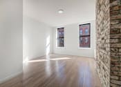 Thumbnail 5 of 7 - an empty living room with a brick wall and wood floors