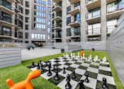 Thumbnail 1 of 29 - A giant chess board with pieces on a lawn in front of a building.