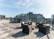 Thumbnail 19 of 37 - Rooftop terrace with wicker seating and city views at 1134 Fulton Street Apartments, Brooklyn, NY 11216