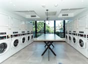 Thumbnail 12 of 37 - Modern communal laundry room with folding table at 1134 Fulton Street Apartments, New York