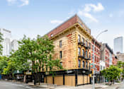 Thumbnail 4 of 5 - A large brick building with a black awning on the corner of a street.