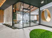 Thumbnail 4 of 29 - A modern office lobby with a glass wall and a green grass area.