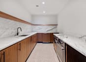 Thumbnail 13 of 56 - the kitchen has marble counter tops and wooden cabinets and stainless steel appliances at The Paxton, Brooklyn, NY 11201