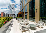 Thumbnail 19 of 56 - A patio with white furniture and a building in the background.