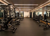 Thumbnail 16 of 56 - A spacious gym with a variety of equipment including treadmills, weights, and exercise machines.