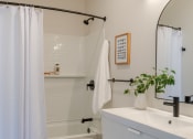 Thumbnail 8 of 42 - a bathroom with a white sink and toilet and a white shower curtain at The 22 Apartments, St. Louis, 63103