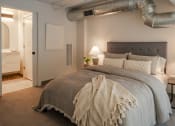 Thumbnail 37 of 42 - a bedroom with a bed and a exposed duct in the ceiling at The 22 Apartments, St. Louis, MO 63103