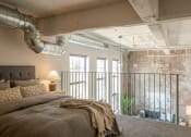 Thumbnail 33 of 42 - a bedroom with a bed and a exposed brick wall at The 22 Apartments, Missouri
