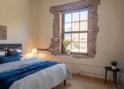 Thumbnail 42 of 42 - a bedroom with a exposed brick wall and a bed with a blue blanket at The 22 Apartments, Missouri, 63103