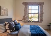 Thumbnail 29 of 42 - a bedroom with a exposed brick wall and a bed with a blue blanket and pillows at The 22 Apartments, Missouri