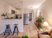 Thumbnail 8 of 11 - a living room with stools and a kitchen with a refrigerator