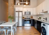 Thumbnail 4 of 28 - a kitchen with white cabinets and black and white appliances at The Draper, Missouri