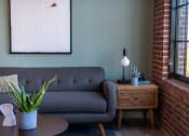 Thumbnail 5 of 42 - a living room with a gray couch and a wooden side table at The 22 Apartments, Missouri