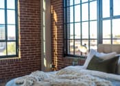 Thumbnail 6 of 42 - a bedroom with large windows and a bed in front of a brick wall at The 22 Apartments, Missouri