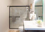 Thumbnail 17 of 42 - a bathroom with a white sink and toilet next to a shower with a glass door at The 22 Apartments, St. Louis Missouri