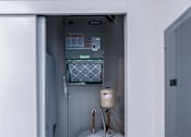 Thumbnail 45 of 61 - A white refrigerator with a water filter and a water heater in a small room.