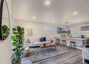 Thumbnail 1 of 27 - A modern living room with a white couch, a coffee table, and a large mirror on the wall.