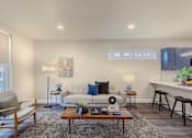 Thumbnail 2 of 27 - A living room with a white couch, a wooden coffee table, and a grey rug.